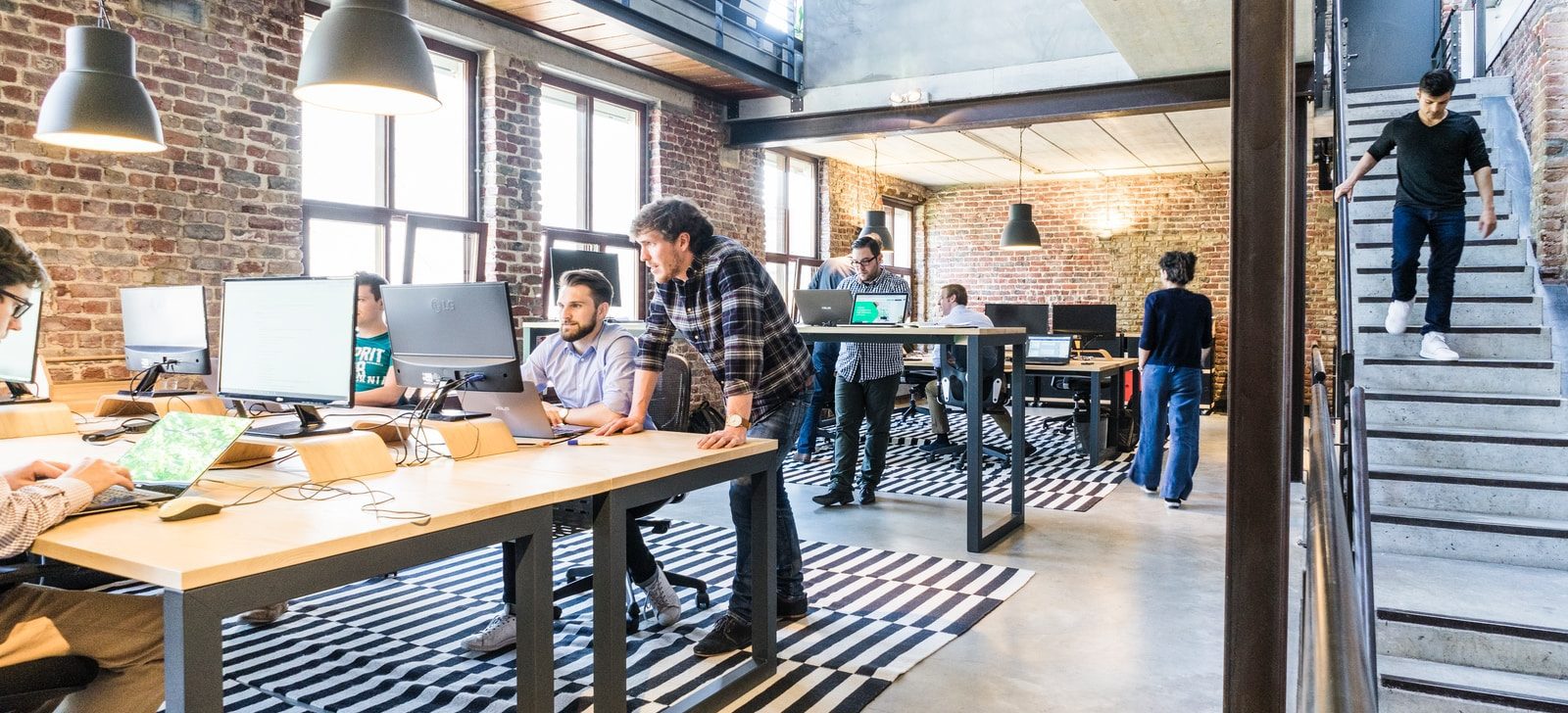 man standing beside another sitting man using computer