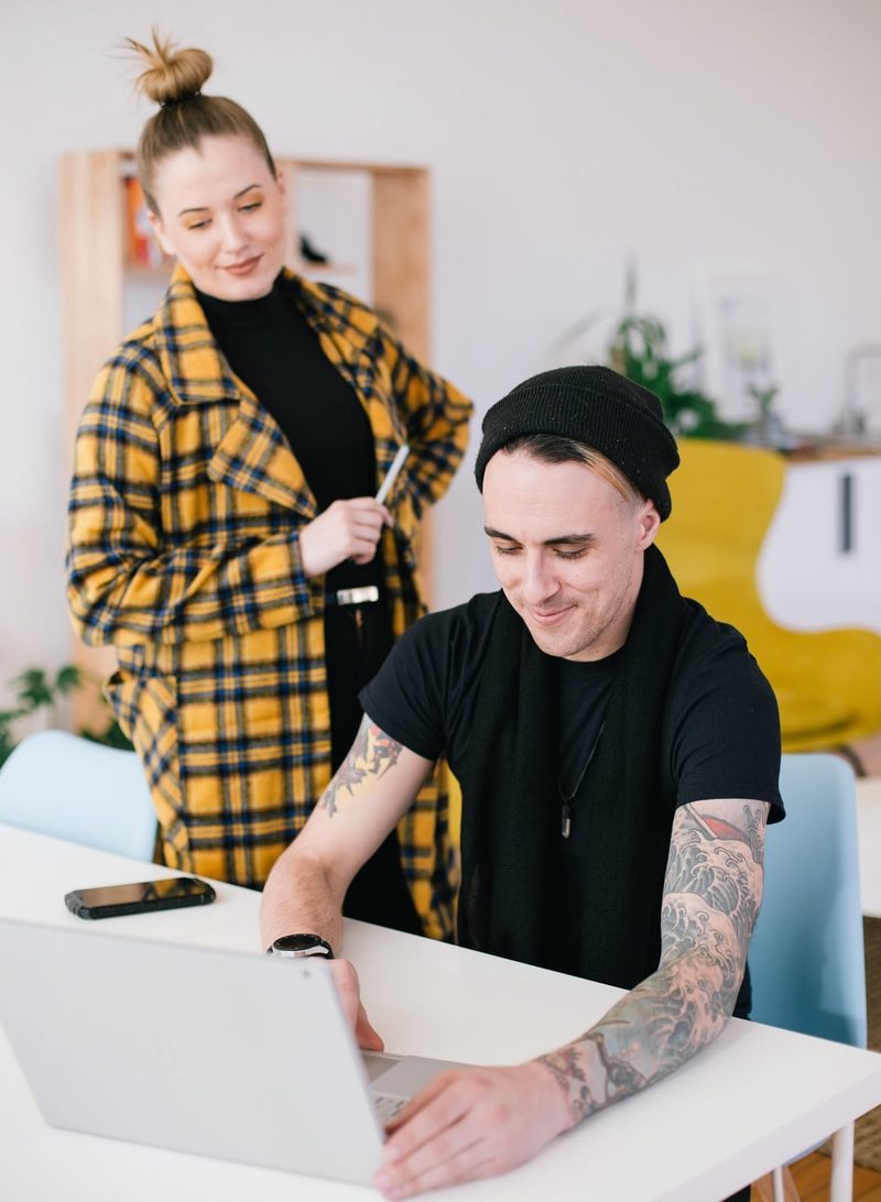 man using laptop beside woman holding pen