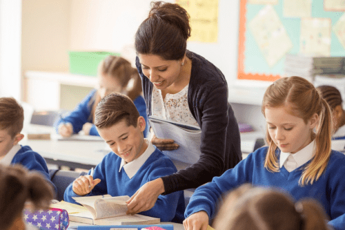 Female Supply Staff Member helping pupil with a text book