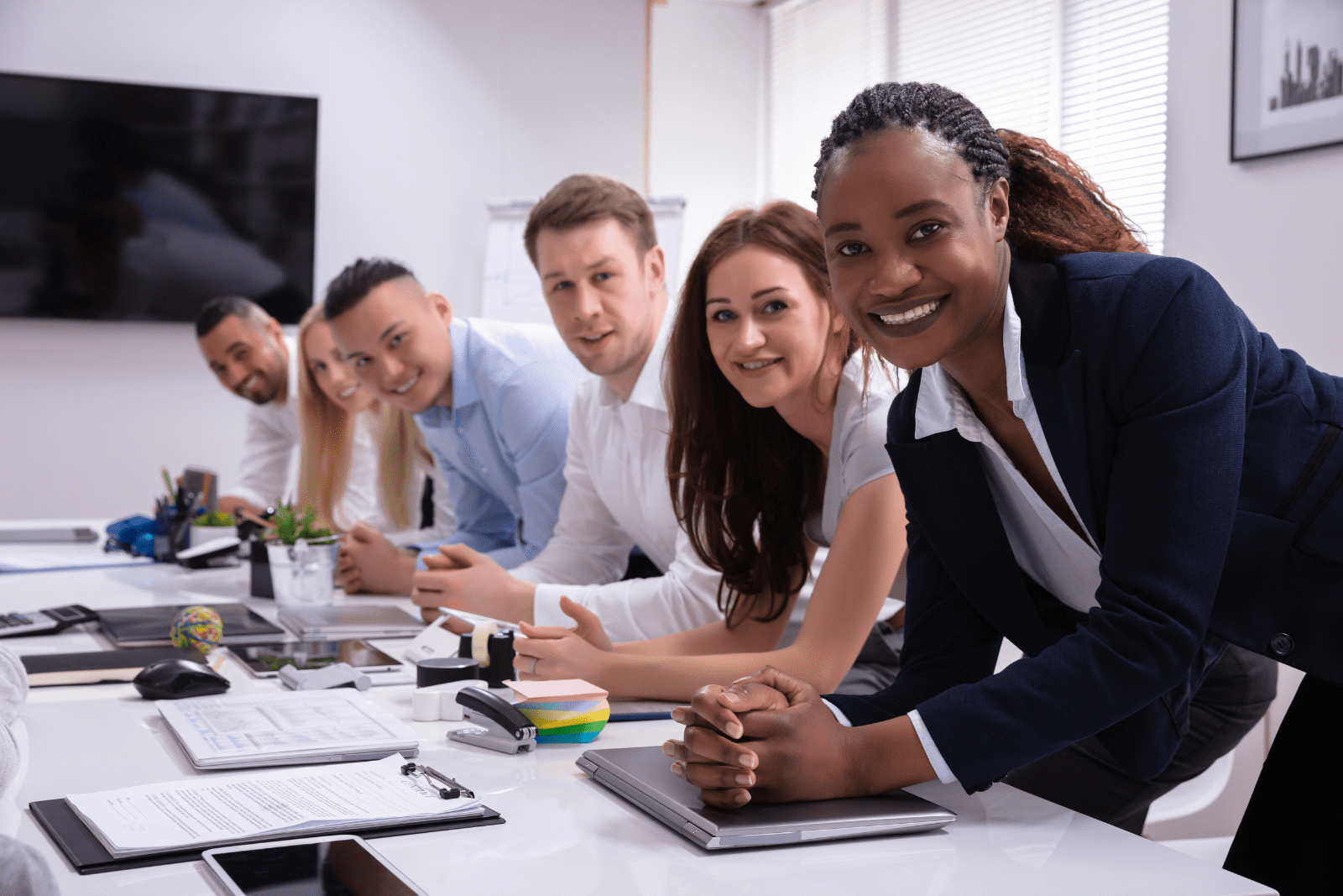 Office Recruitment -Team of office people in a meeting facing and smiling at the camera.