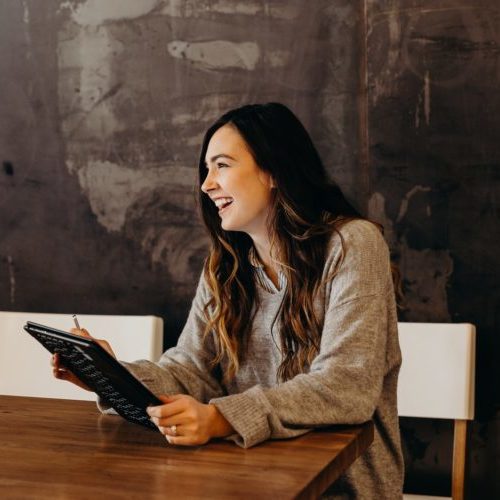 woman sitting around table holding tablet