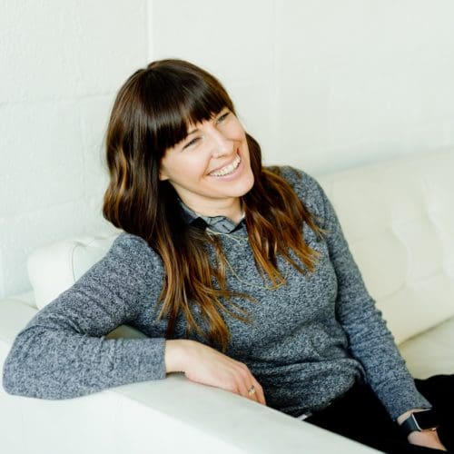 femme en pull gris assise sur une chaise blanche