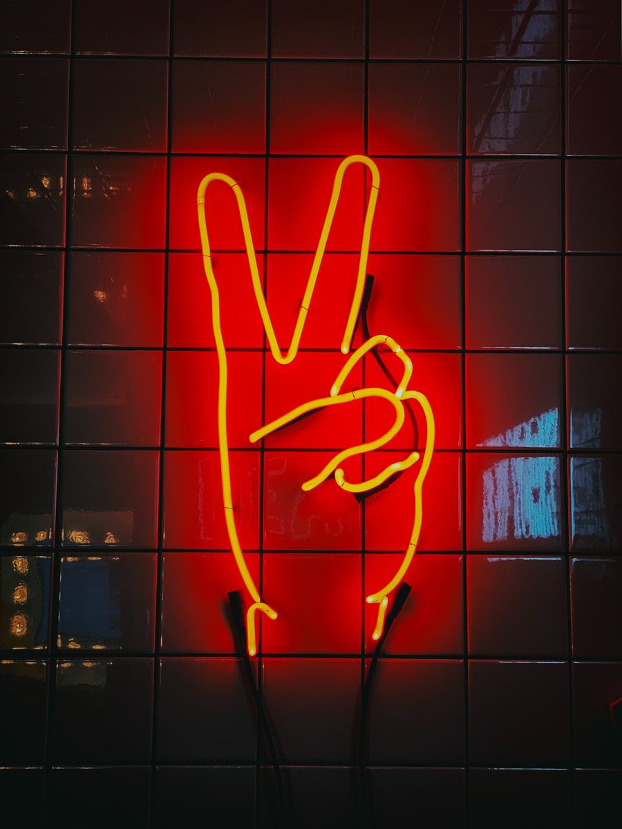 Peace sign neon signage on the wall of [hire] gaming recruitment agency