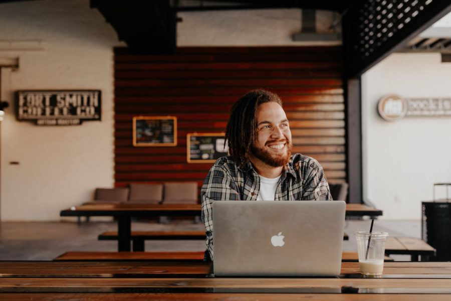 man in black and white plaid dress shirt sitting in front of silver macbook