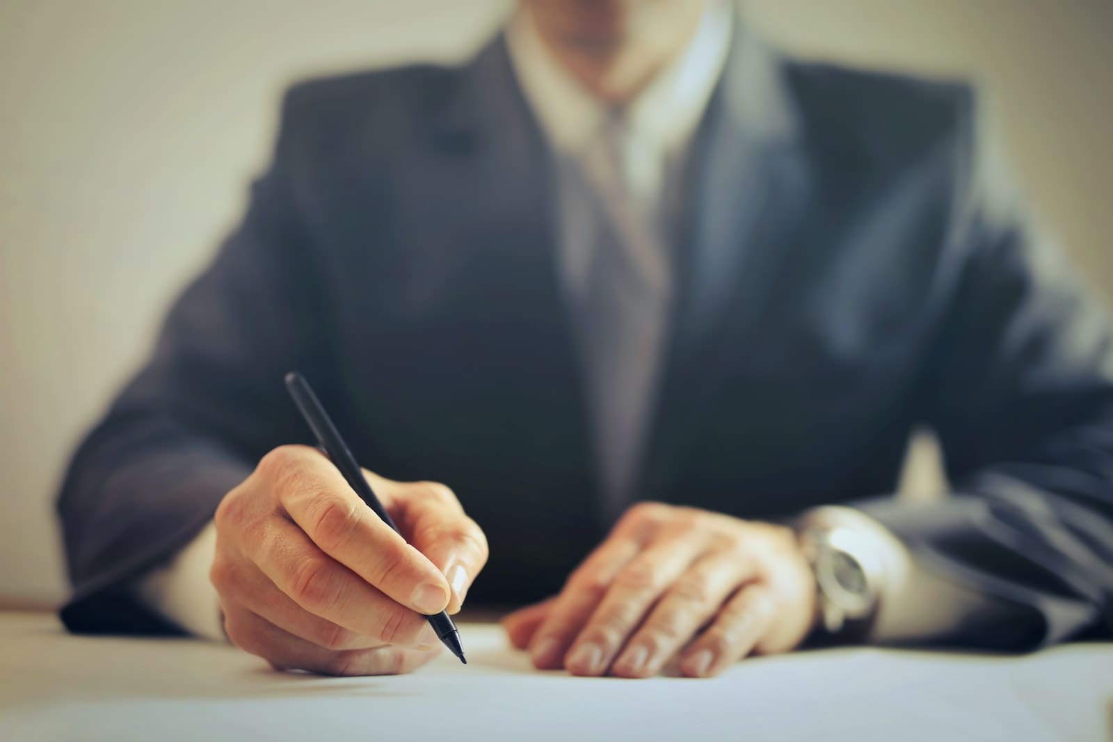 Crop businessman signing contract in office