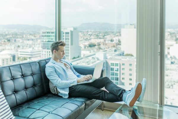 man sitting on sofa while using laptop